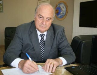 Imagem homem de terno e gravata com caneta na mão assinando documento