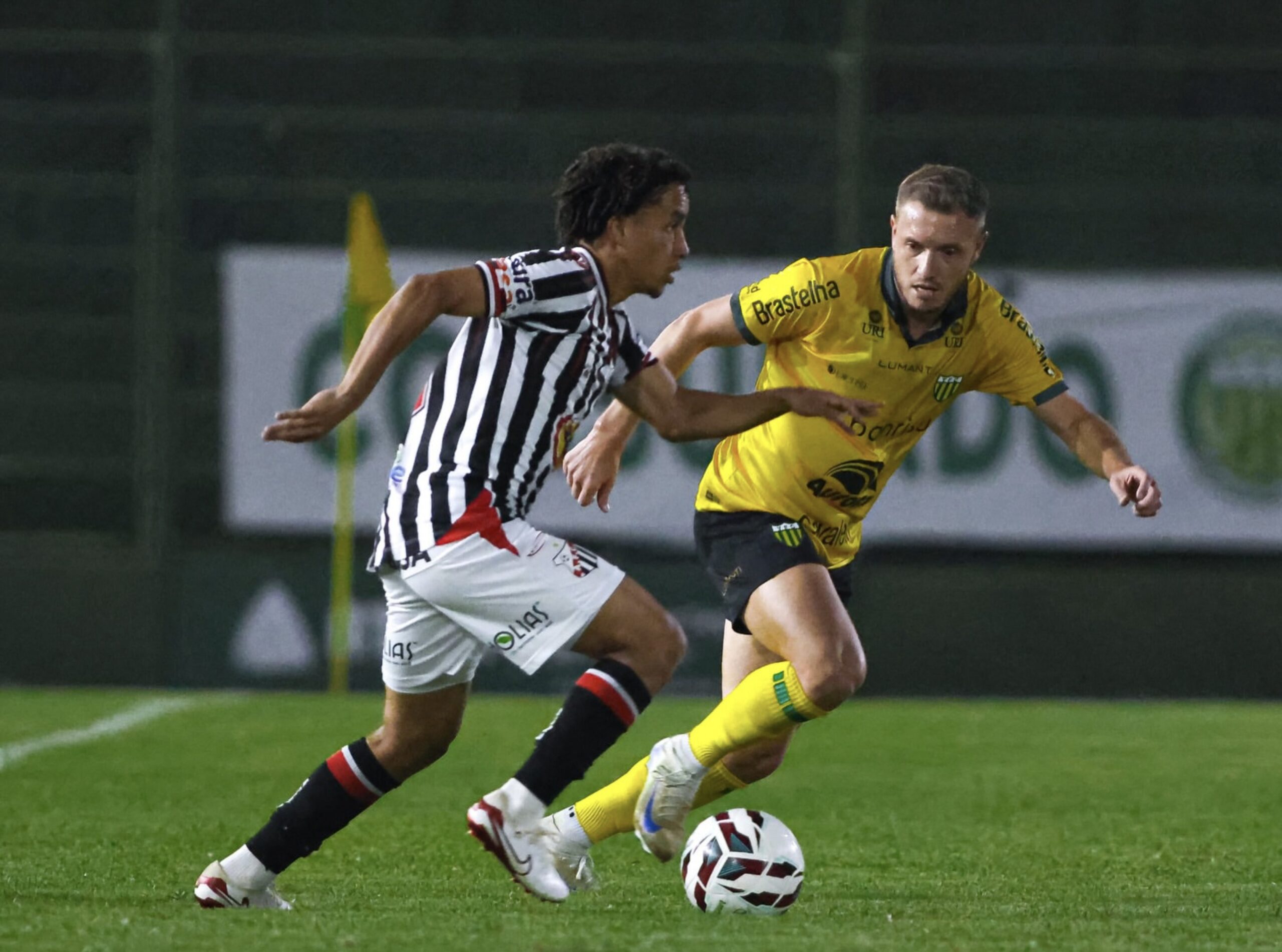 Imagem jogadores disputando a bola em campo gramado