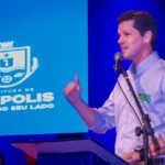 Imagem homem de camisa branca falando ao microfone