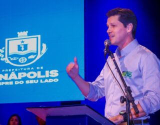 Imagem homem de camisa branca falando ao microfone