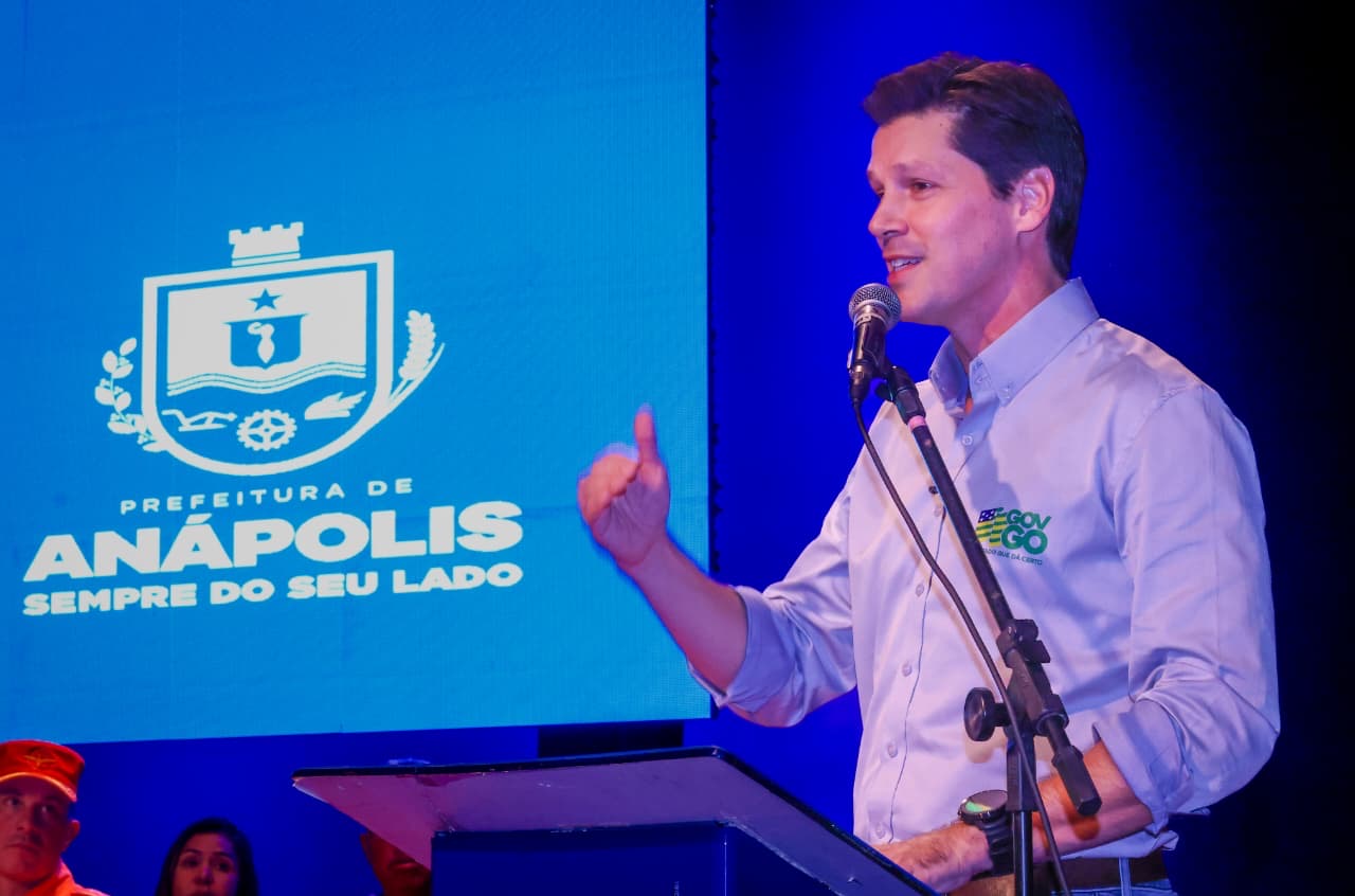 Imagem homem de camisa branca falando ao microfone