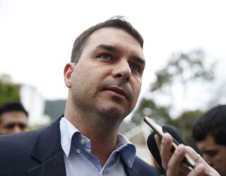 Imagem homem de terno sem gravata olhado para cima com celular a sua frente para gravar