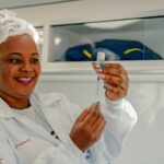 Imagem mulher de branco manuseia seringa e medicamento