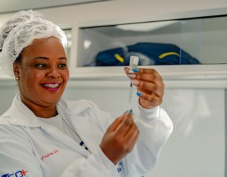 Imagem mulher de branco manuseia seringa e medicamento