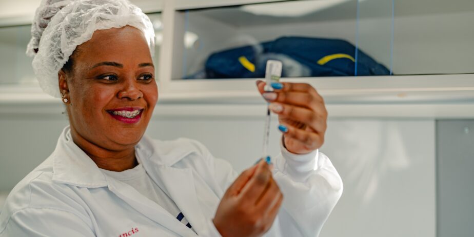 Imagem mulher de branco manuseia seringa e medicamento
