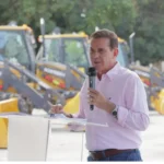 Imagem homem camisa branca segurando microfone Vanderlan entrega maquinários a 39 municípios. (Foto: Divulgação)