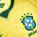 Imagem camisa amarela com detalhes verdes e cinco estrelas sobre o escudo Camisa Seleção Brasileira