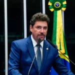 Imagem homem de terno e gravata falando ao microfone
