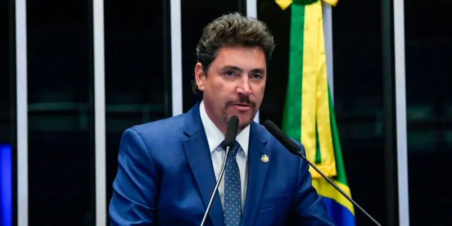 Imagem homem de terno e gravata falando ao microfone