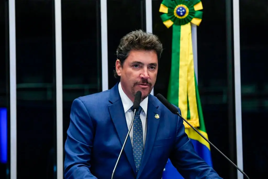 Imagem homem de terno e gravata falando ao microfone
