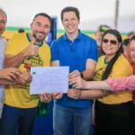 Imagem pessoas segurando um documento e sorrindo para foto