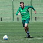 Imagem jogador de uniforme verde correndo com a bola no gramado