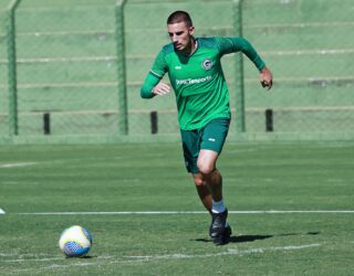 Imagem jogador de uniforme verde correndo com a bola no gramado