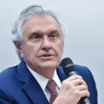 Imagem homem de terno segurando microfone com a mão