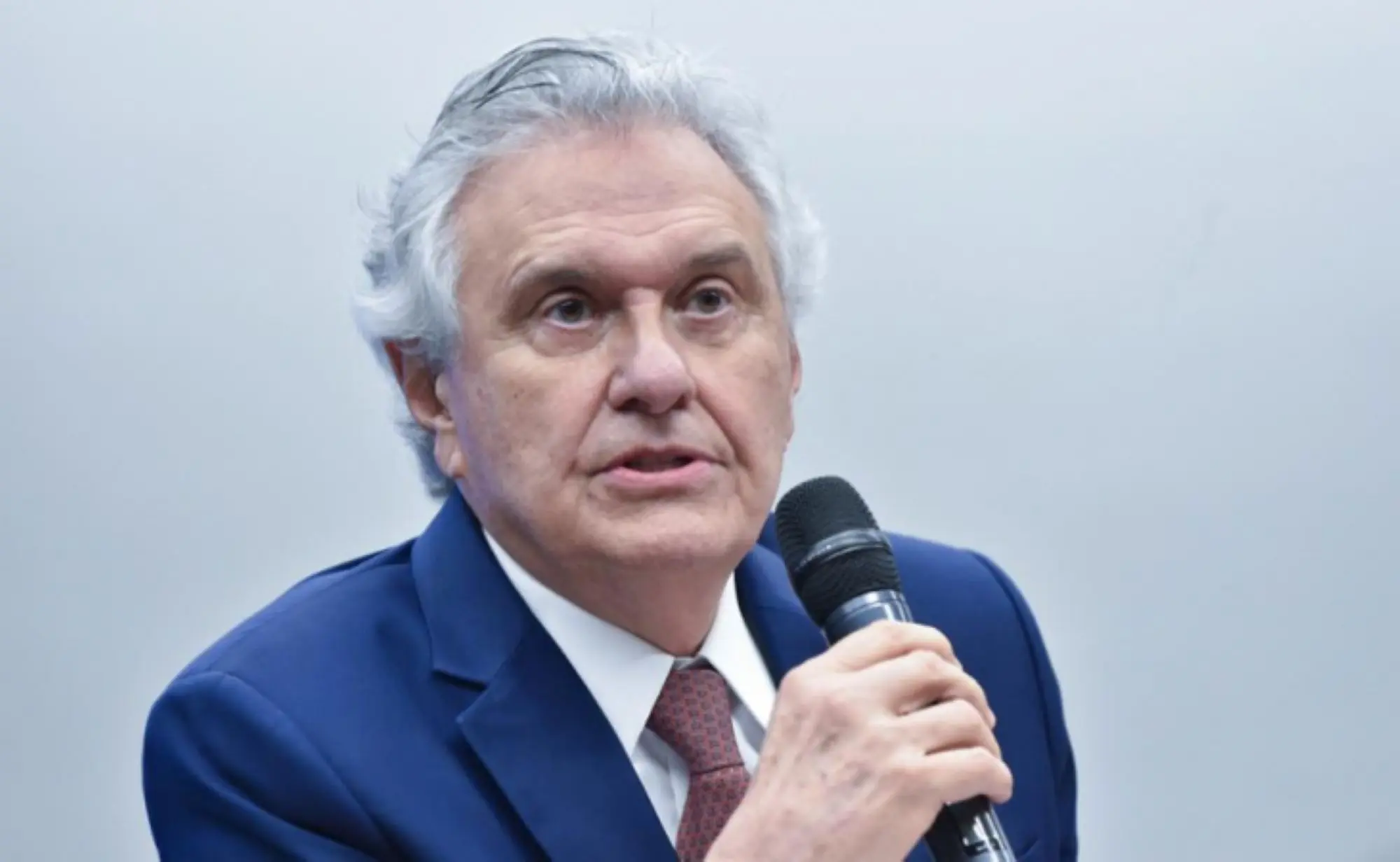 Imagem homem de terno segurando microfone com a mão