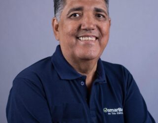 Imagem homem de braços cruzados e camisa azul sorrindo
