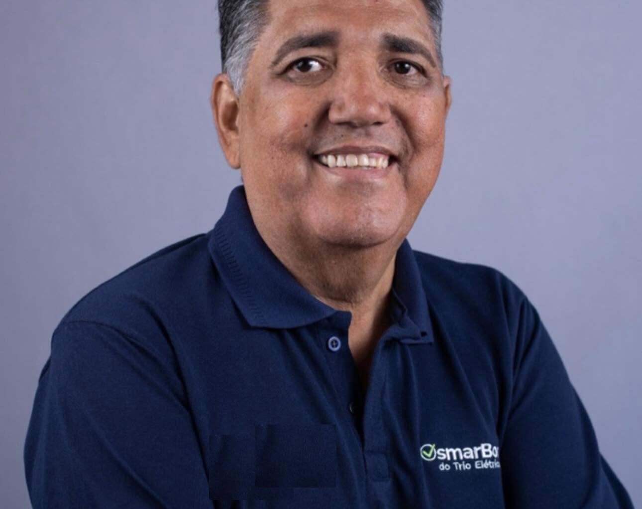 Imagem homem de braços cruzados e camisa azul sorrindo