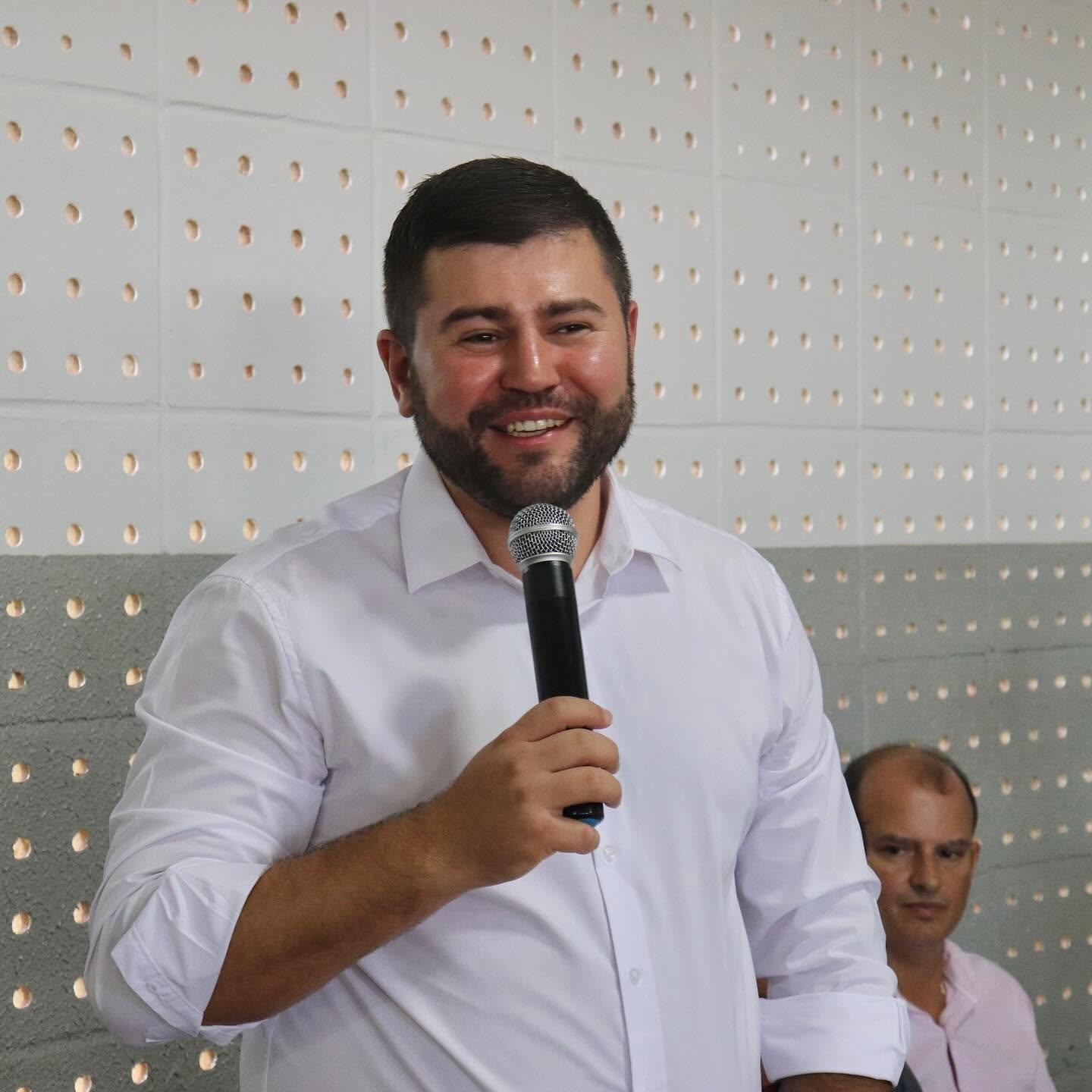 Imagedm homem de camisa branca segurando microfone sorrindo