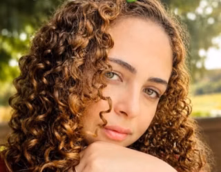 Imagem mulher cabelo cacheado com a mão no rosto