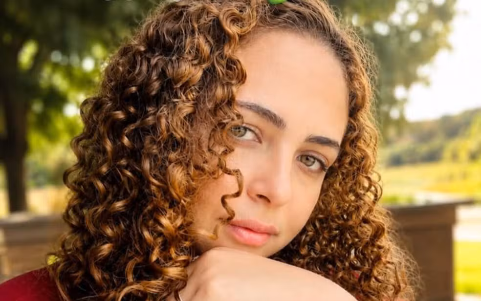 Imagem mulher cabelo cacheado com a mão no rosto