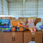 Imagem de brinquedos em cima de caixas de papelão em um galpão.