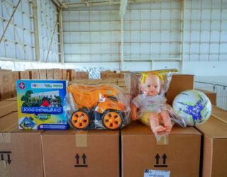 Imagem de brinquedos em cima de caixas de papelão em um galpão.