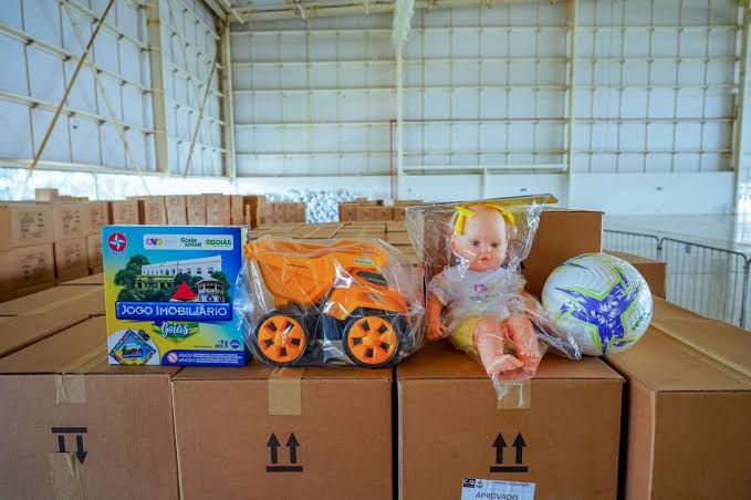 Imagem de brinquedos em cima de caixas de papelão em um galpão.