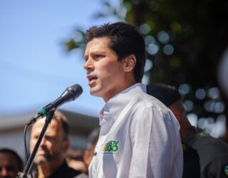 Imagem homem camisa branca falando ao microfone