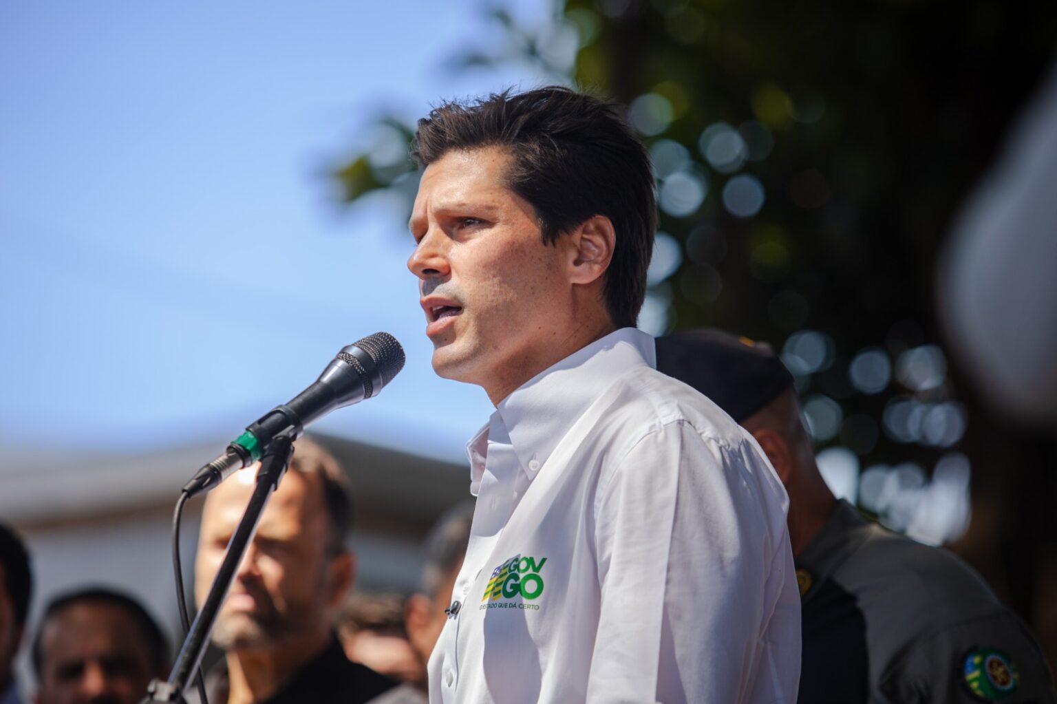 Imagem homem camisa branca falando ao microfone