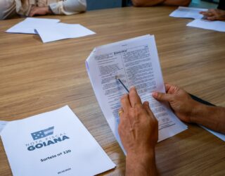 Imagem mãos segurando folha de papel Sorteio da Nota Fiscal Goiana