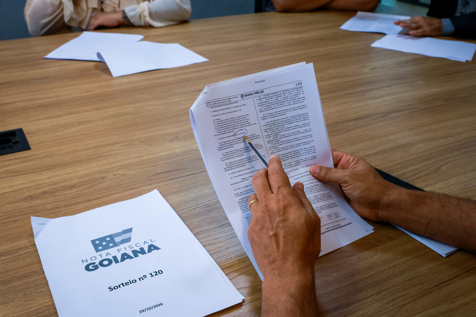 Imagem mãos segurando folha de papel Sorteio da Nota Fiscal Goiana