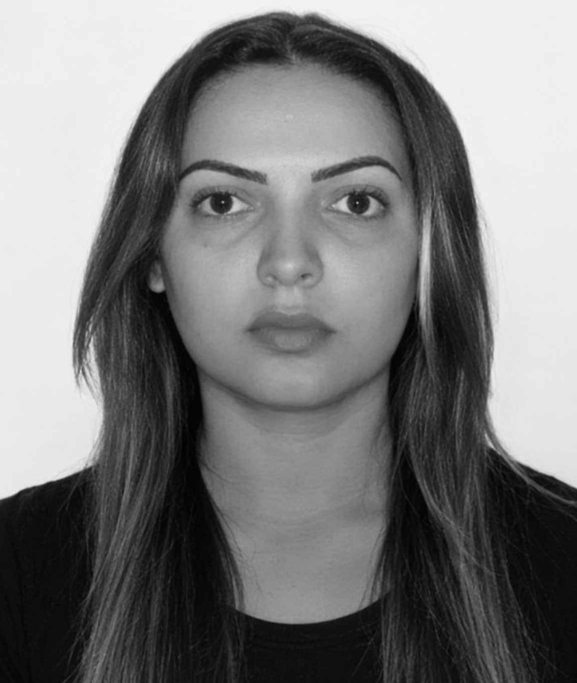 Imagem de uma mulher com camisa preta, olhando para a foto e séria. A imagem está em preto e branco.
