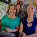 Imagem de senhoras sorrindo para foto, utilizando o transporte público.