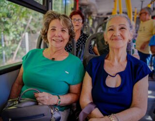 Imagem de senhoras sorrindo para foto, utilizando o transporte público.
