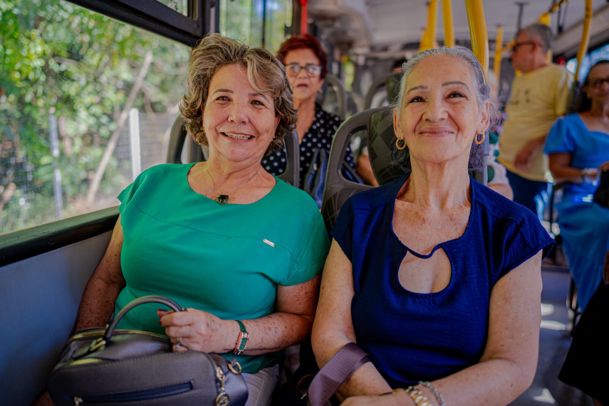 Imagem de senhoras sorrindo para foto, utilizando o transporte público.