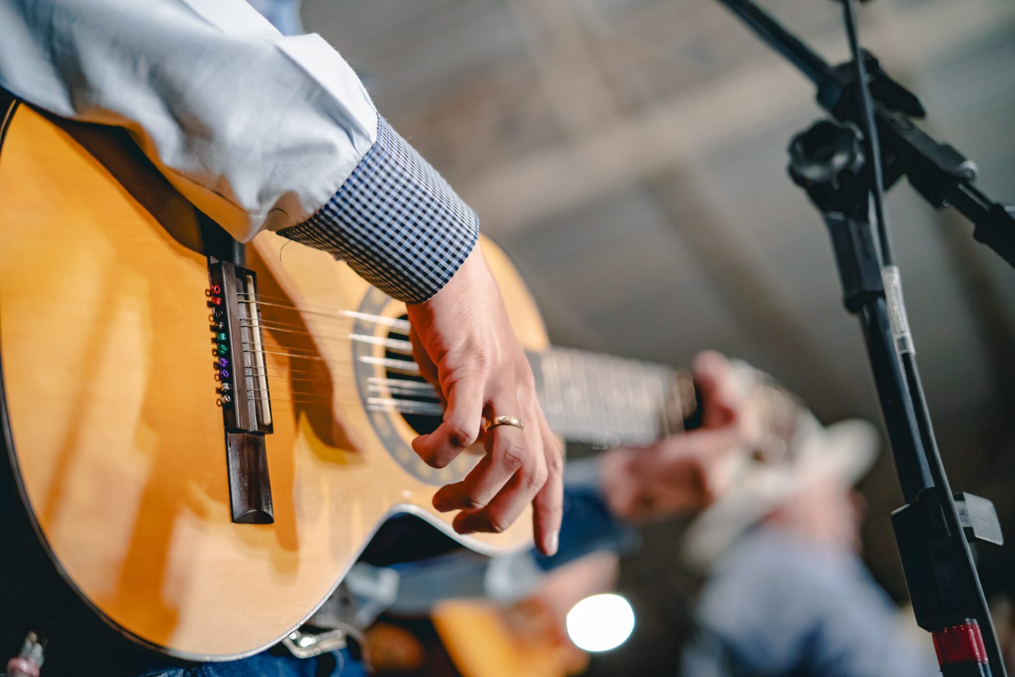 Imagem de um homem tocando viola, na imagem aparece apenas os braços e mãos do homem.