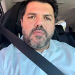 Imagem do Prefeito Márcio Corrêa, usando camisa azul clara, dentro do carro, o cinto de segurança transpassado.