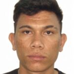 Imagem de um homem olhando para a foto, usando camiseta preta e com o fundo branco.