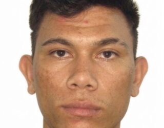 Imagem de um homem olhando para a foto, usando camiseta preta e com o fundo branco.