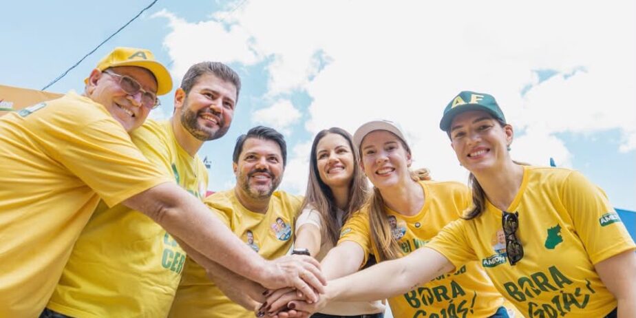 Imagem de Amilton Filho, sua esposa Carol, irmã Andreia, pai, Prefeito Márcio e esposa. Todos vestindo camiseta amarela de camapnha, com as mãos juntas, em clima de equipe.