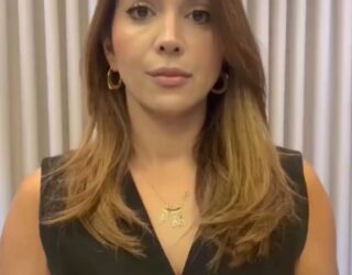 Imagem da Delegada Aline Lopes da DPCA Anápolis. Ela está com cabelos soltos, olhando para a câmera e usando roupas pretas.