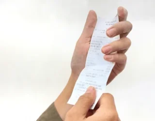Imagem de uma mão segurando um comprovante de pagamento,