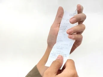 Imagem de uma mão segurando um comprovante de pagamento,